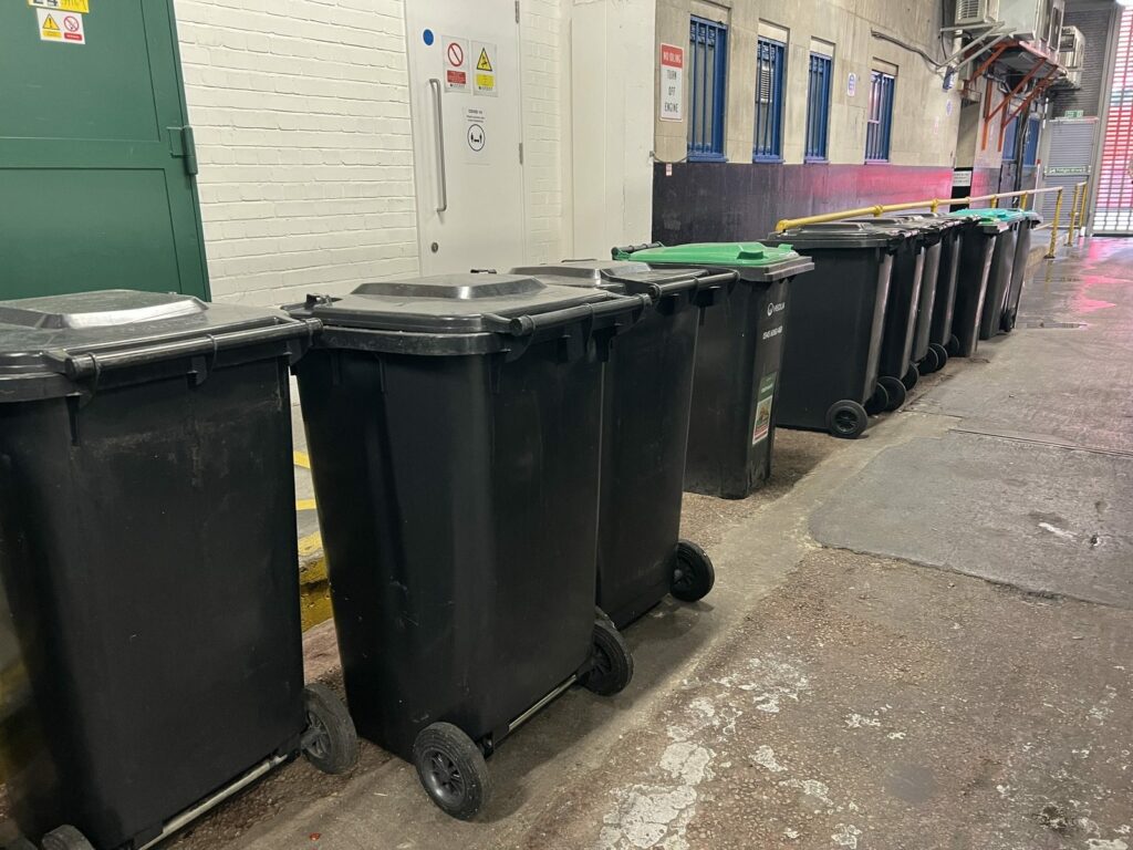 A row of two-wheel commercial bins in a London basement service area