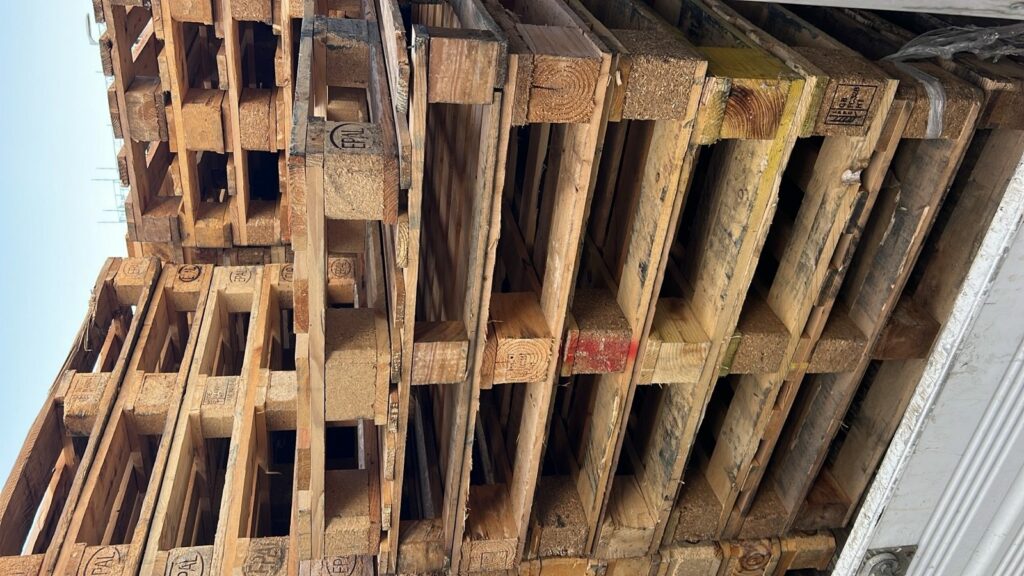 Mixed used pallets stacked inside a Capital Recycle caged tipper after a London collection